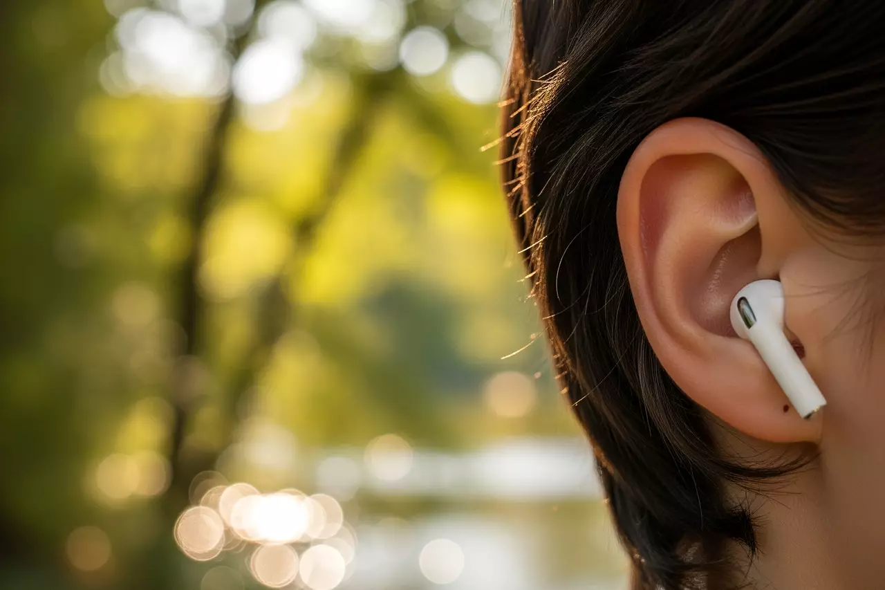Sumérgete en la experiencia auditiva de la naturaleza, desconectando del ruido exterior. Primer plano del oído de una persona con un auricular, con un fondo natural suavemente desenfocado.